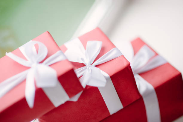 three red boxes with gifts tied with a white ribbon near the window